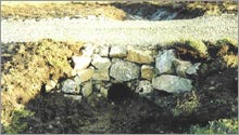 Construction of a permanent stone access track through a peat bog, utilising local materials.